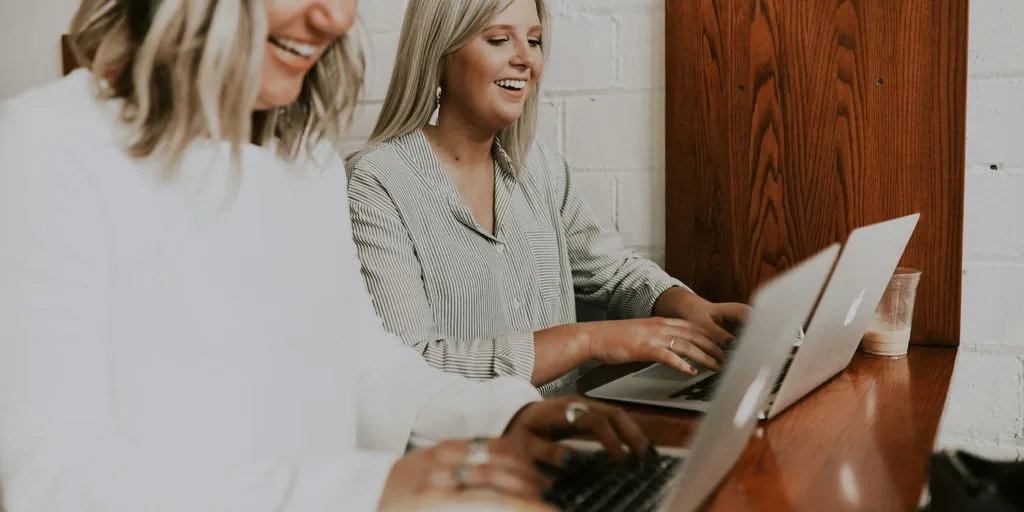 two women using laptops