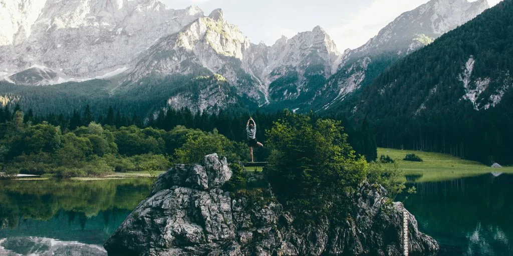 person standing on rock formation surrounded by body of water