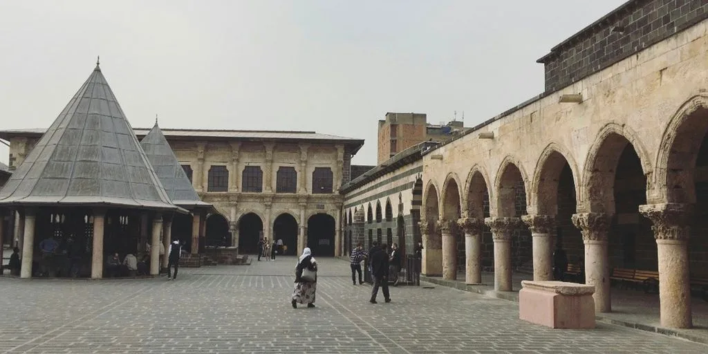 a group of people walking around a courtyard with buildings in the background