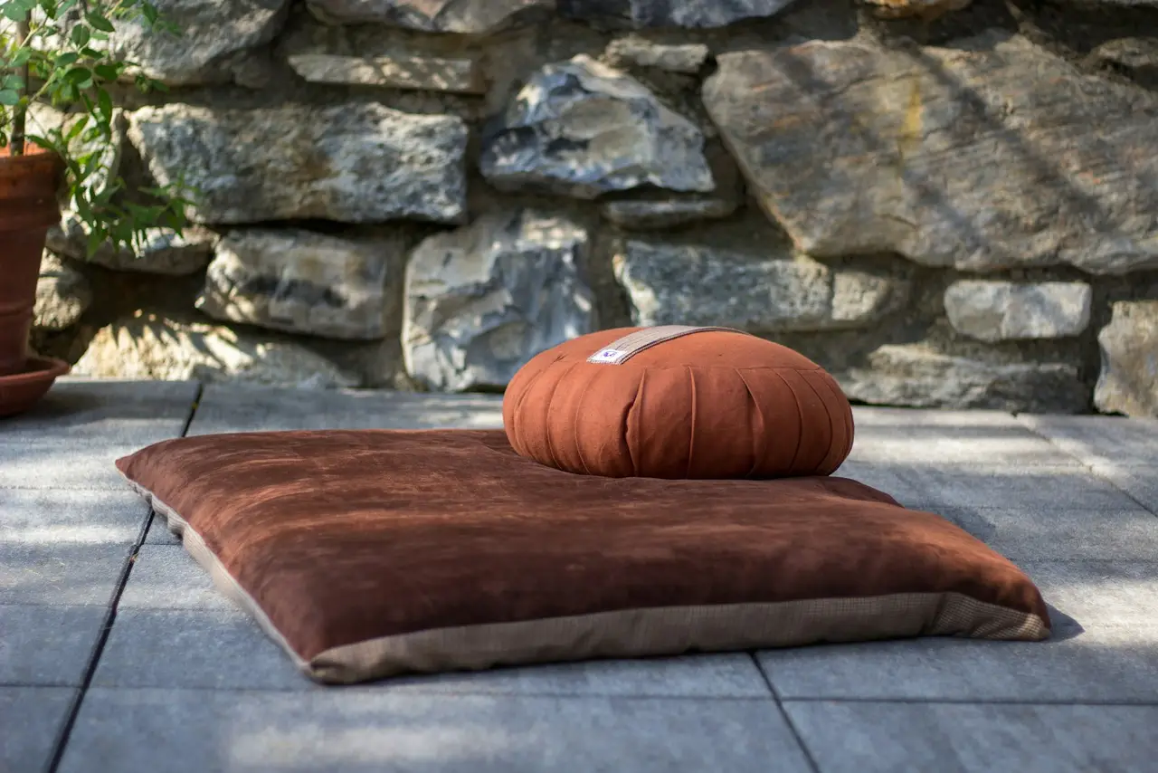Un coussin de méditation placé sur un sol en bois.